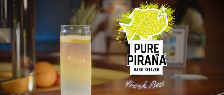 Stilstaand beeld van een glas Pure Pirana hard seltzer op een bar met een citroentje erin. Afkomstig uit de productvideo.